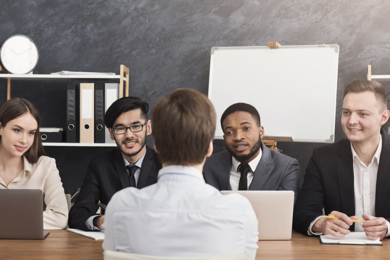 réunion en entreprise Groupe de personnes en réunion, discutant autour d'une table, avec un tableau en arrière-plan.